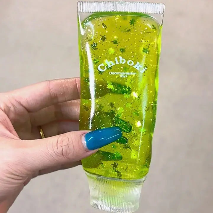 Balle anti-stress en forme de tube avec gel vert translucide et détails trèfle porte-bonheur