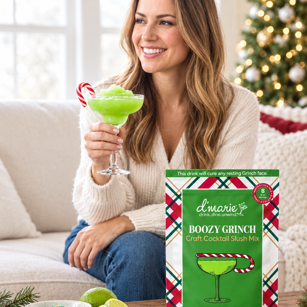 Cocktail glacé vert Boozy Grinch garni d’une canne en sucre, dégusté près de son sachet D’Marie dans un décor de Noël